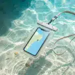 Waterproof phone pouch with lanyard floating in clear tropical water, smartphone displaying a map