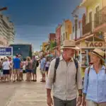 Cruise port shore excursions: couple walking by taco stand and sign, tourists and colorful waterfront shops